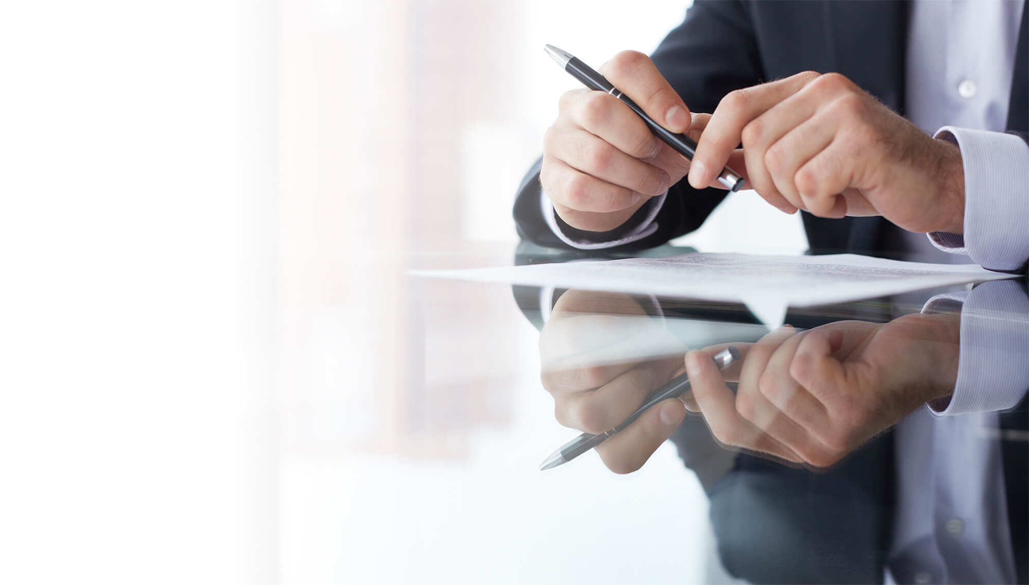 A person writing on paper with a pen.