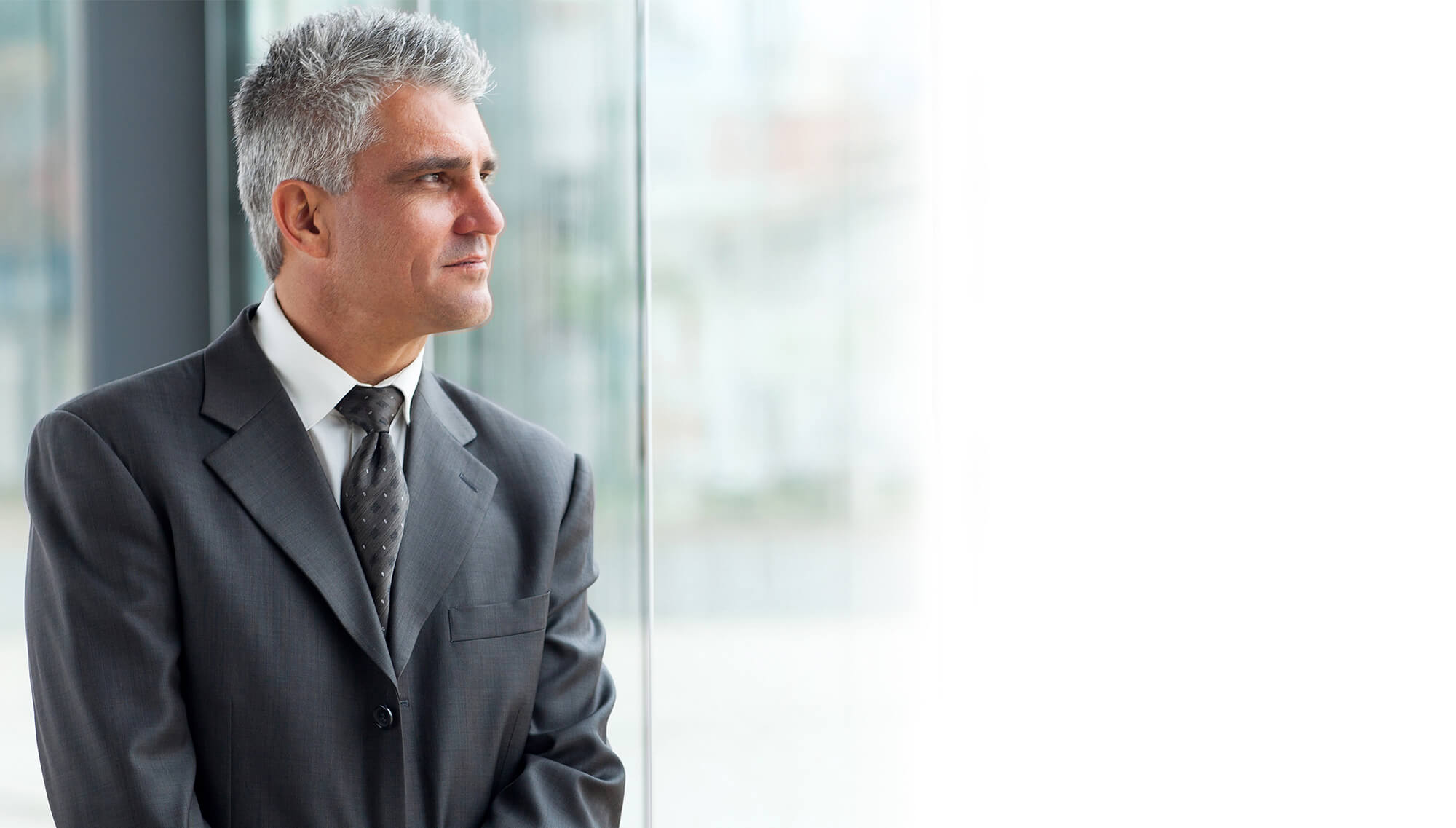 A man in suit and tie looking out of the window.